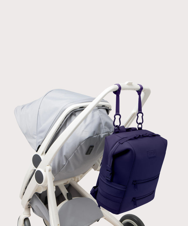 Large Indi backpack in a jewel-toned, deep blue with strong purple undertones., side angle view hanging on a stroller