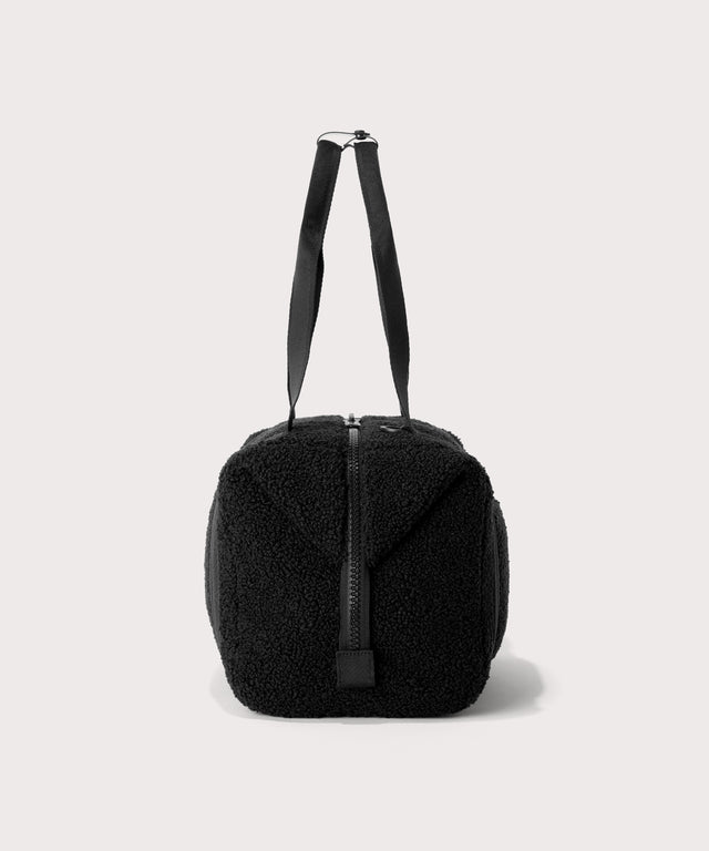 Medium landon carryall in a black., side view  In a  Faux Shearling  a soft, wool-like plush made with recycled materials