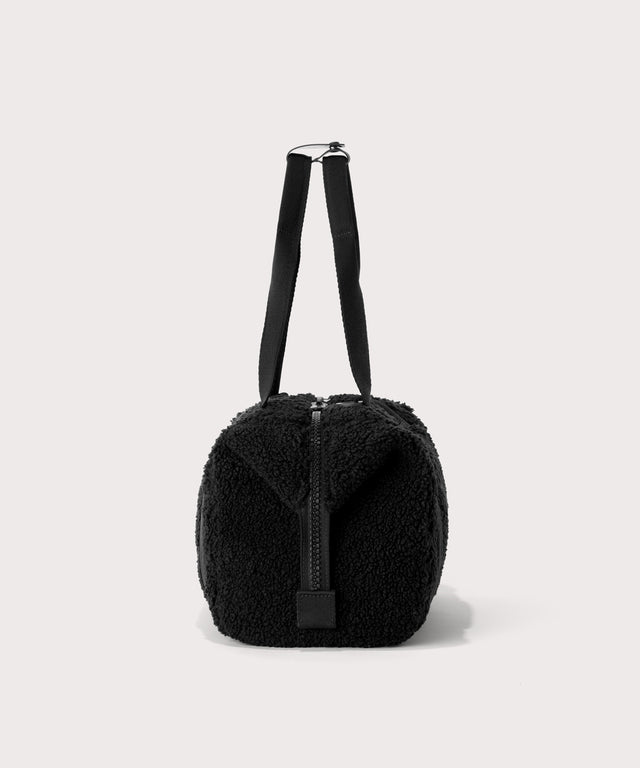 small landon carryall in a black., side view  In a  Faux Shearling  a soft, wool-like plush made with recycled materials