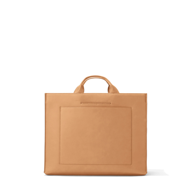 Dagne Dover medium vegan Daily Tote in brown revealing the exterior phone pocket and exterior luggage sleeve.