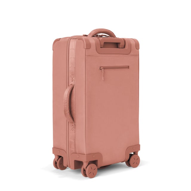 3/4 back view of Seattle carry-on rolling luggage 23.5” in warm dust showing side handle and back zippered phone/passport pocket