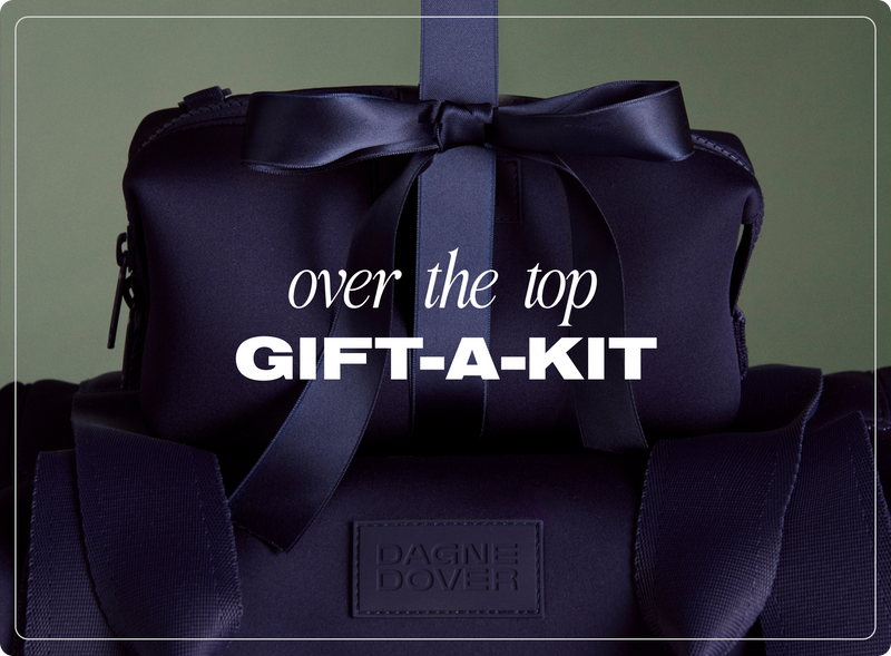Navy gift bag with a bow labeled 'over the top GIFT-A-KIT' on a dark green background.