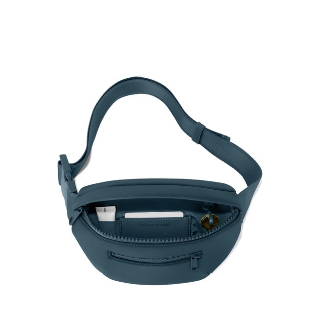 Dagne Dover Ace Fanny Pack in moonlight blue unzipped, exposing the interior pockets. hover