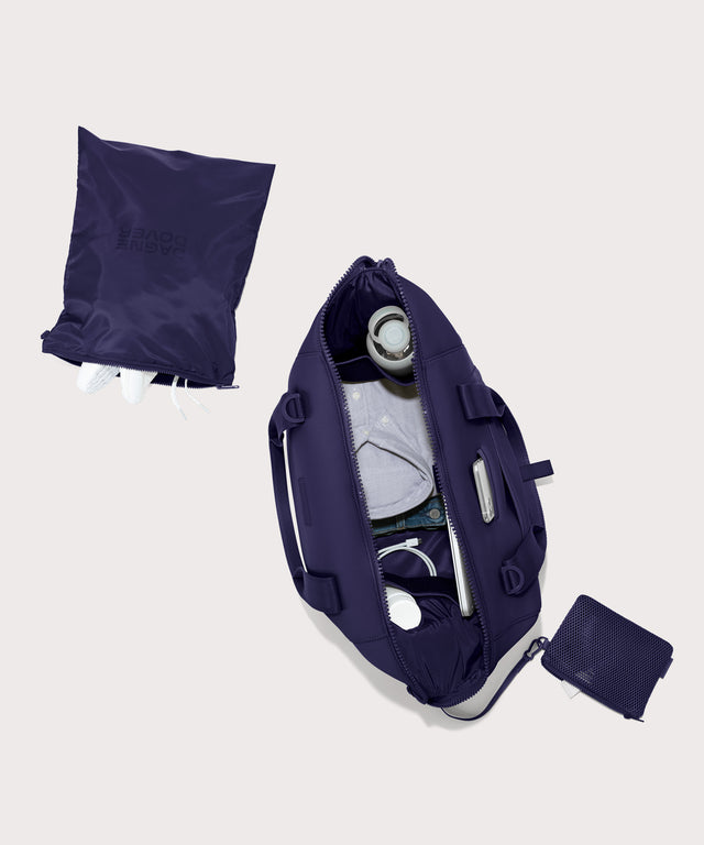 Large Landon Carryall in a jewel-toned, deep blue with strong purple undertones unzipped, top down view. 
