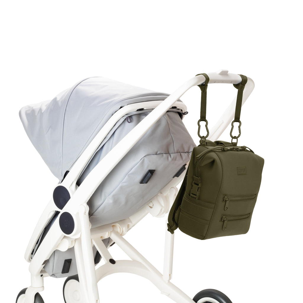 Dagne Dover Small Indi Diaper Backpack in dark green attached to a stroller.