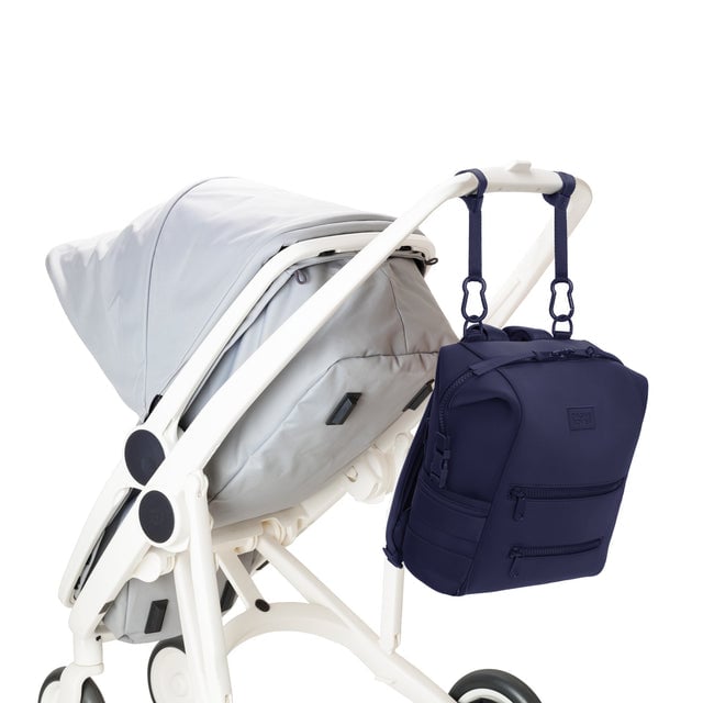 Dagne Dover Medium Indi Diaper Backpack in dark blue attached to a stroller.