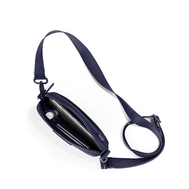 Dagne Dover Mara Phone Sling unzipped in navy blue seen from above, exposing the interior card slots.