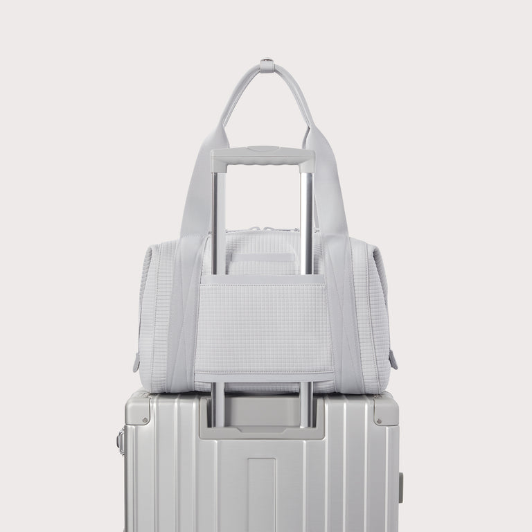 Dagne Dover Medium Landon Carryall in a muted light grey with classic waffle texture displaying luggage sleeve. EDEAE8.
