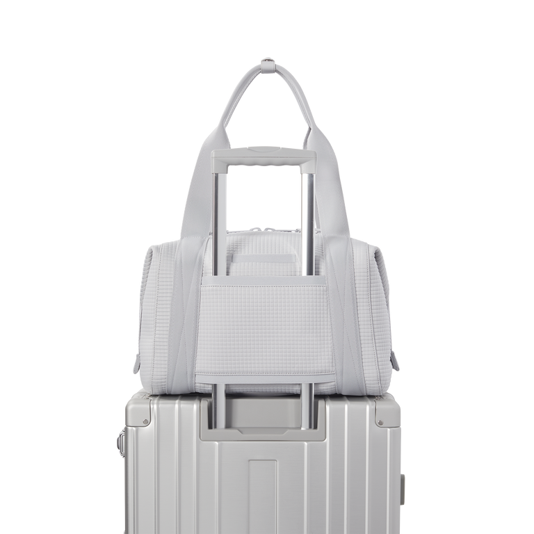 Dagne Dover Medium Landon Carryall in a muted light grey with classic waffle texture displaying luggage sleeve.