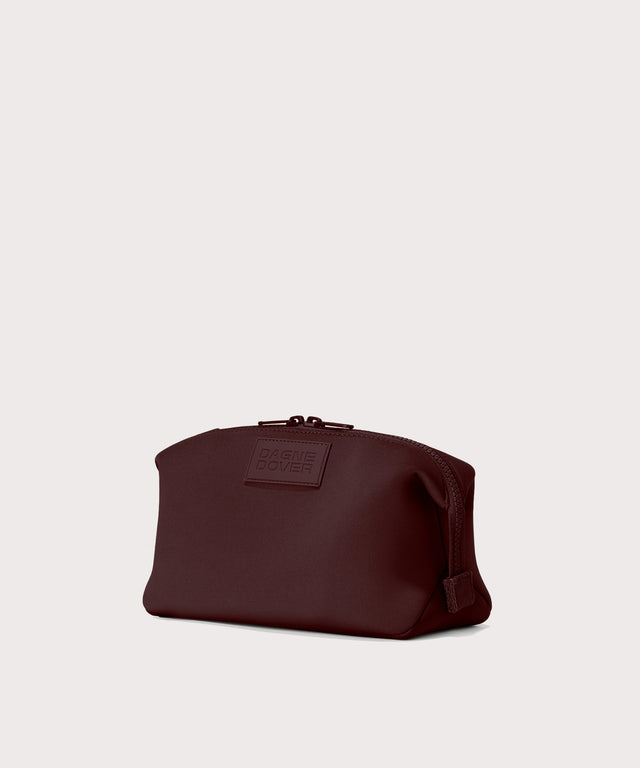 Dagne Dover Large Hunter Toiletry Bag in a deep brown with purple undertones seen from an angle.