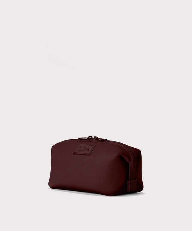Dagne Dover Small Hunter Toiletry Bag in a deep brown with purple undertones seen from an angle.