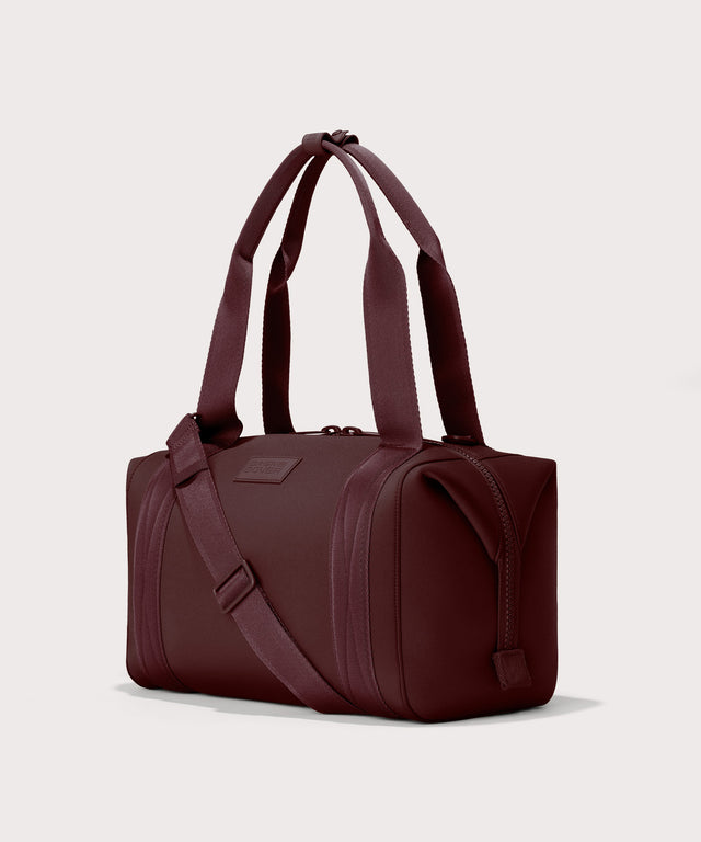 Dagne Dover Medium Landon Carryall in a deep brown with purple undertones seen from an angle.