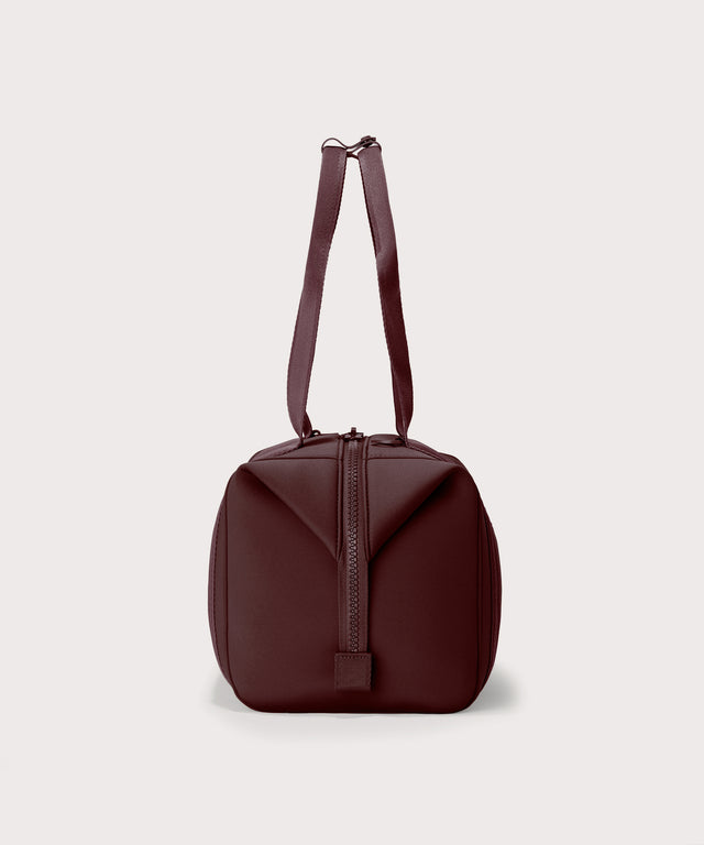 Dagne Dover Medium Landon Carryall in a deep brown with purple undertones seen from the side.
