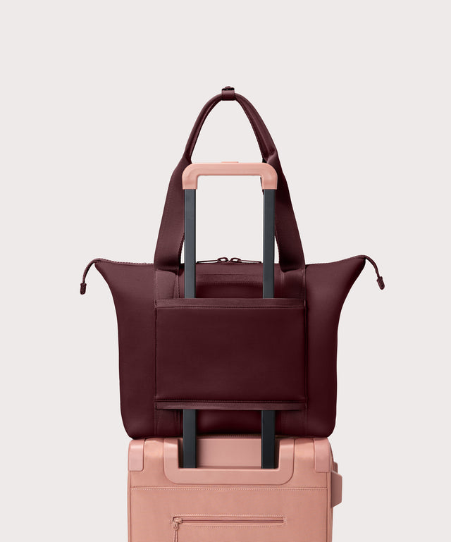 Tote  bag in a  deep brown with purple undertones reminiscent of maroon seen from the back view on suitcase.
