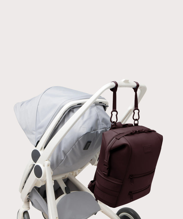 Dagne Dover Large Indi Diaper Backpack in a deep brown with purple undertones attached to a stroller.