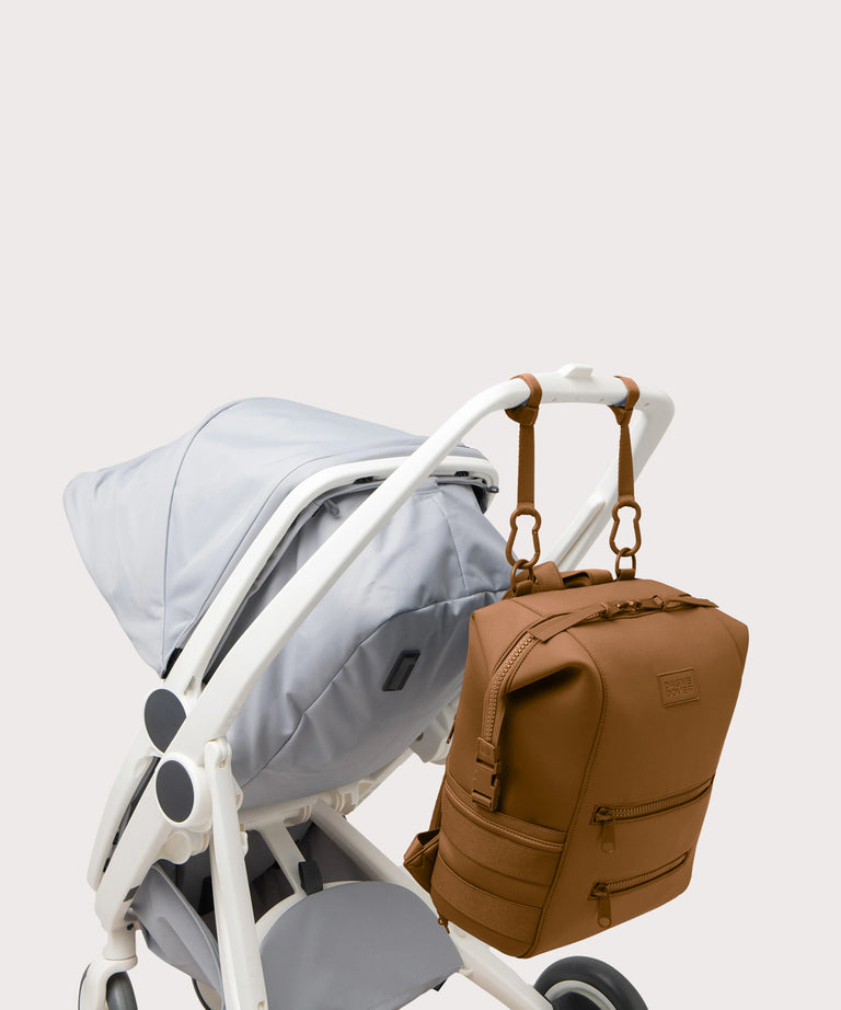 Large Indi backpack in a saturated, warm medium-brown with burnt orange undertones., side angle view hanging on a stroller
