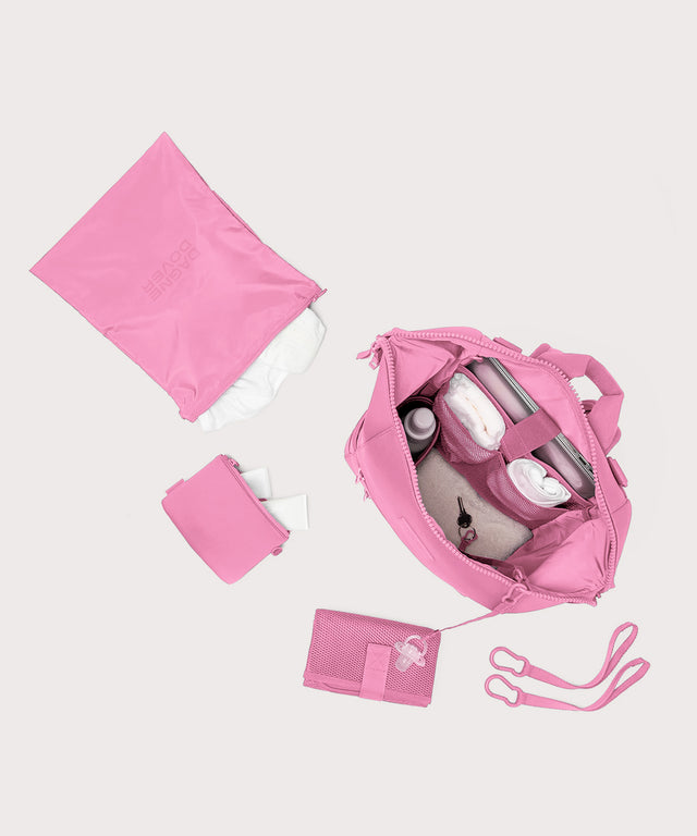 Dagne Dover Large Indi Diaper Backpack in a true bubble gum pink unzipped showing it's water resistant bag, interior pockets, and changing mat.