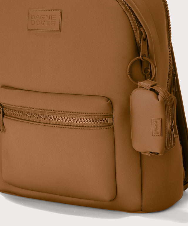 Hunter keychain in a saturated, warm medium-brown with burnt orange undertones . front angle showing keychain on a backpack. 