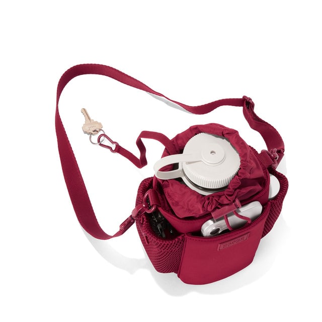 Dagne Dover Sloan Water Bottle Sling in a punchy, saturated deep red seen from above containing a water bottle and accessories. hover