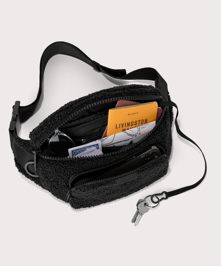 Jax fanny pack in a black . unzipped, top down view.  In a  Faux Shearling  a soft, wool-like plush made with recycled materials
