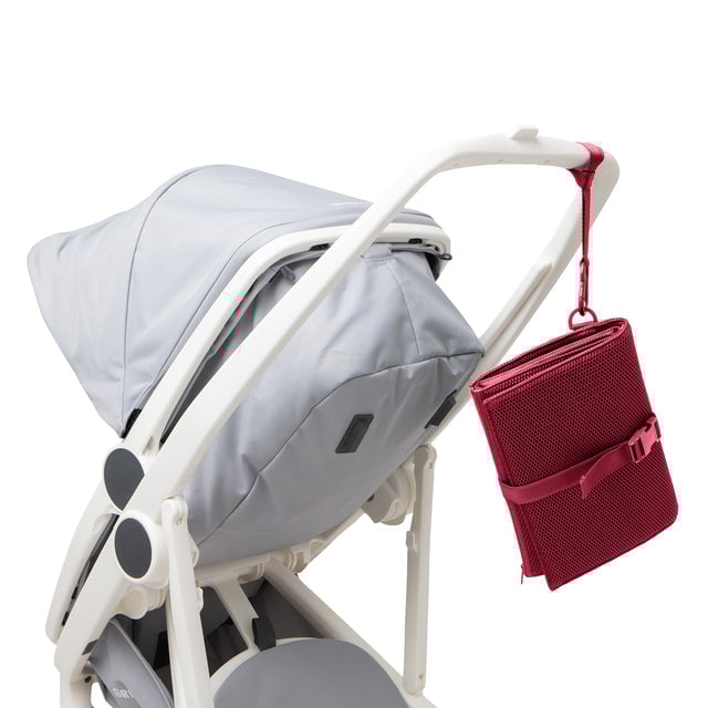 Dagne Dover Joey Changing Kit in spice red strapped to the handle of a stroller.