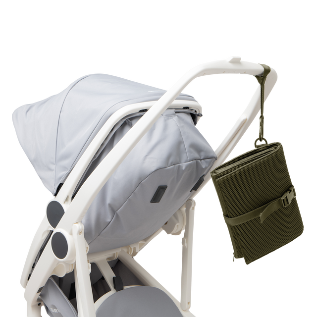 Dagne Dover Joey Changing Kit in dark green strapped to the handle of a stroller.