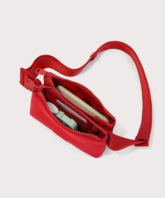 Dagne Dover Bennie Sling in a fiery, saturated red leaning toward orange unzipped displaying interior of both pouches.