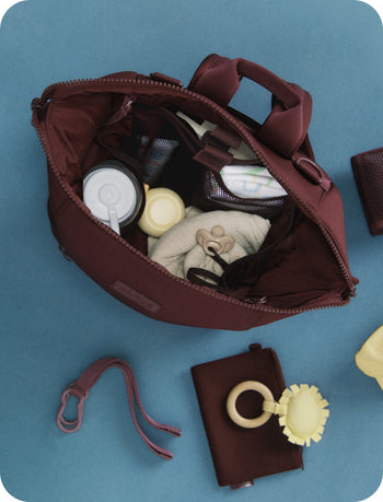 Open brown bag with baby items on a blue background
