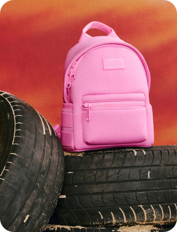 Pink backpack on a stack of tires with an orange background