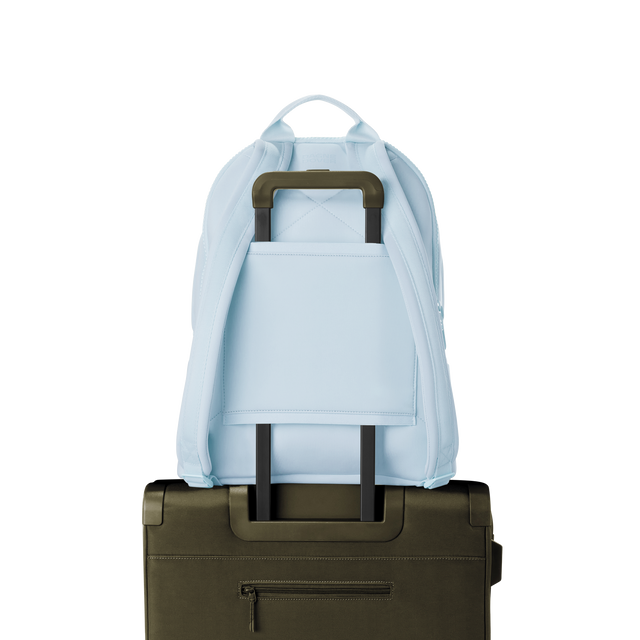 Dagne Dover large Dakota Neoprene Backpack in An airy, lighter sky blue strapped to luggage with the neoprene luggage-handle sleeve.