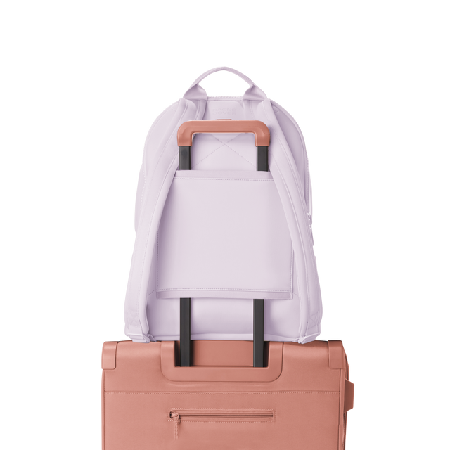 Dagne Dover large Dakota Neoprene Backpack in A soft purple with grey undertones strapped to luggage with the neoprene luggage-handle sleeve.
