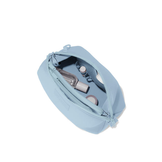 Dagne Dover Large Hunter Toiletry Bag in an airy, lighter sky blue unzipped and seen from above.
