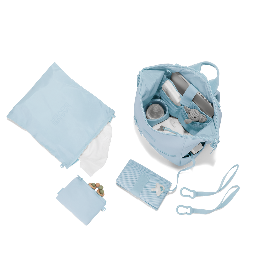Dagne Dover medium Indi Diaper Backpack in an airy, lighter sky blue showing it's water resistant bag, interior pockets, and changing mat.
