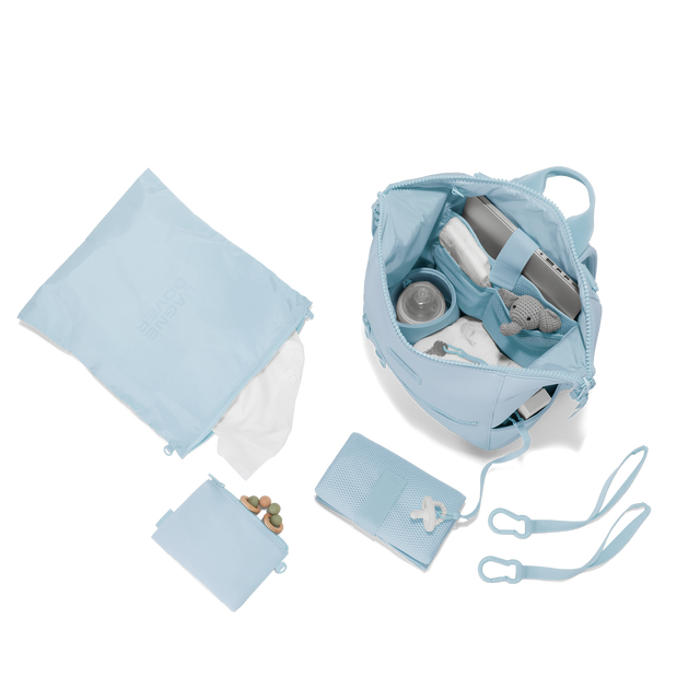 Dagne Dover medium Indi Diaper Backpack in an airy, lighter sky blue showing it's water resistant bag, interior pockets, and changing mat. Hover

