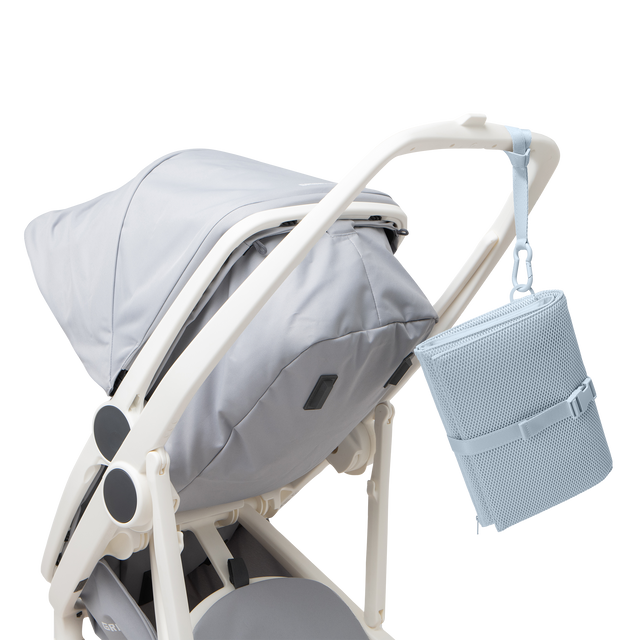 Dagne Dover Joey Changing Kit in an airy, lighter sky blue strapped to the handle of a stroller.
