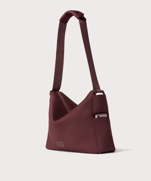 Large Shoulder bag in a deep brown with purple undertones reminiscent of maroon seen from the angle view showing phone pocket.
