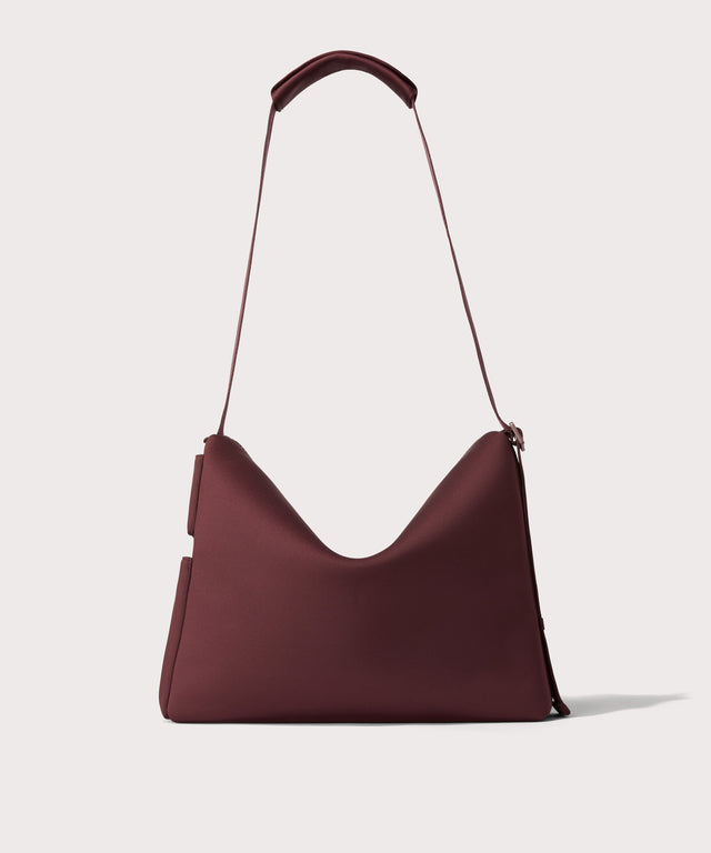 Large Shoulder bag in a  deep brown with purple undertones reminiscent of maroon seen from the back view showing phone pocket.
