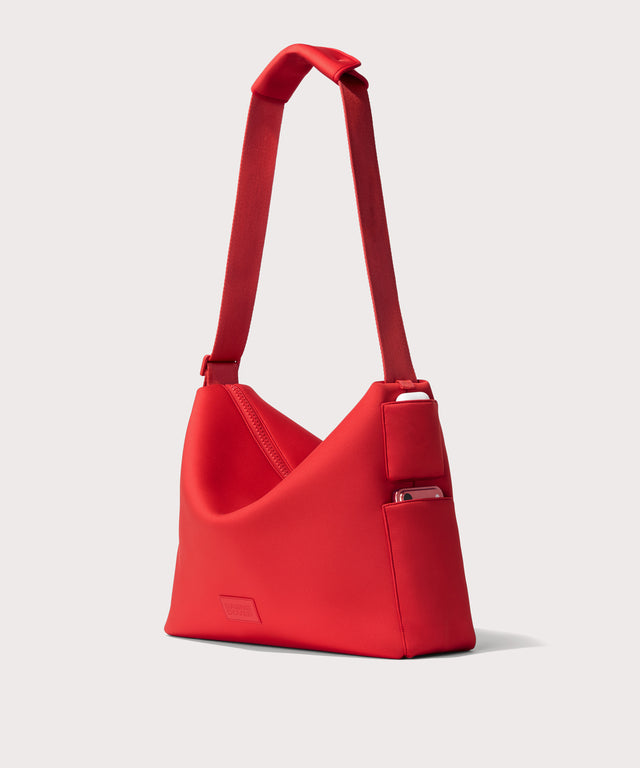 Large Shoulder bag in a fiery, saturated red leaning toward orange seen from the angle view showing phone pocket.
