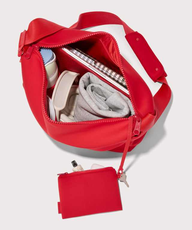 Large  Shoulder bag in a fiery, saturated red leaning toward orange seen from the top down view showing interior mesh pouch.
