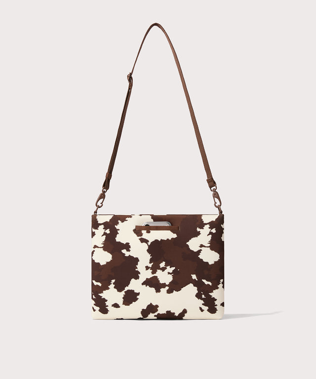 14 inch laptop shoulder bag in a cow print seen from the back view. 
