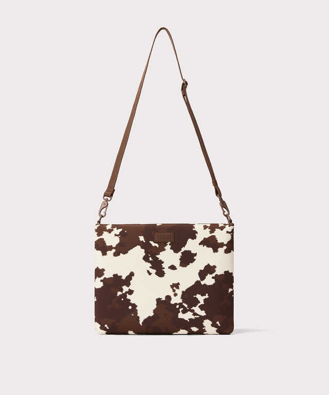 14 inch laptop shoulder bag in a cow print seen from the front view. 
