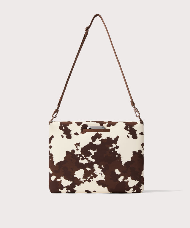 16 inch laptop shoulder bag in a cow print seen from the back view. 
