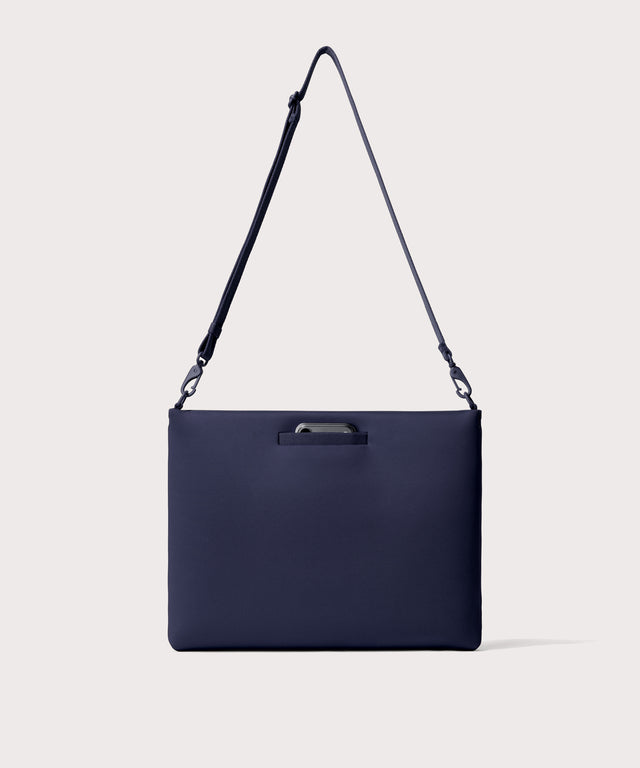 16 inch laptop shoulder bag in navy blue  seen from the back view showing phone pocket.
