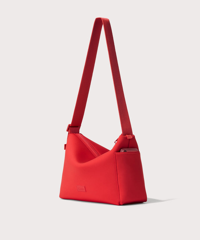 Shoulder bag in a fiery, saturated red leaning toward orange seen from the angle view showing phone pocket.
