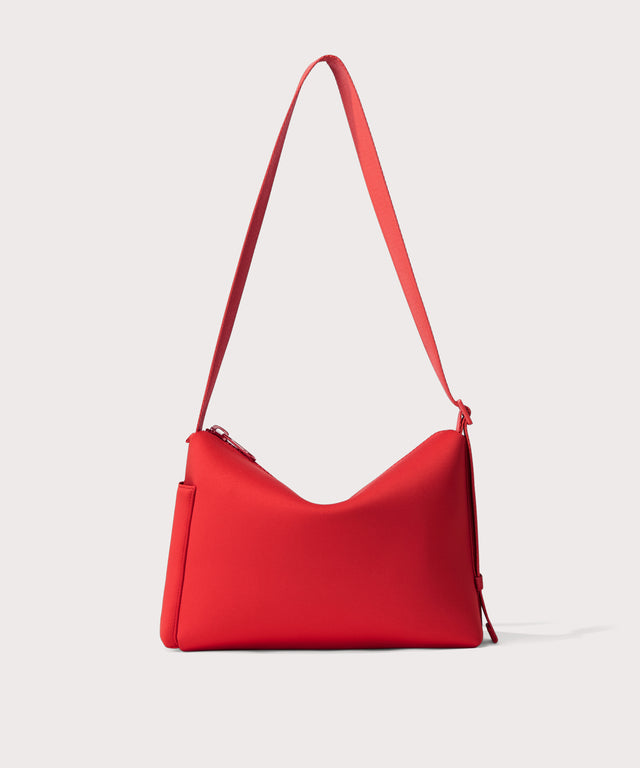 Shoulder bag in a  fiery, saturated red leaning toward orange seen from the back view showing phone pocket.
