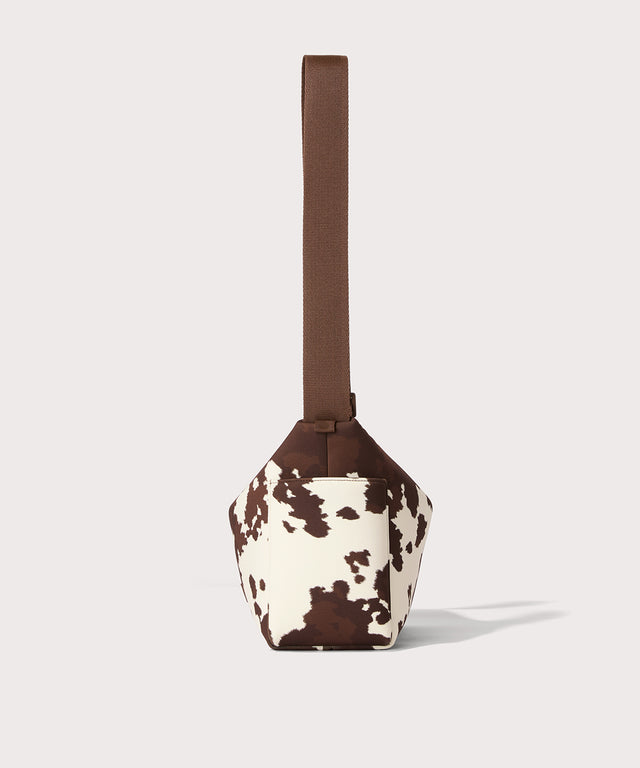 Shoulder bag in a cow print seen from the side view. 