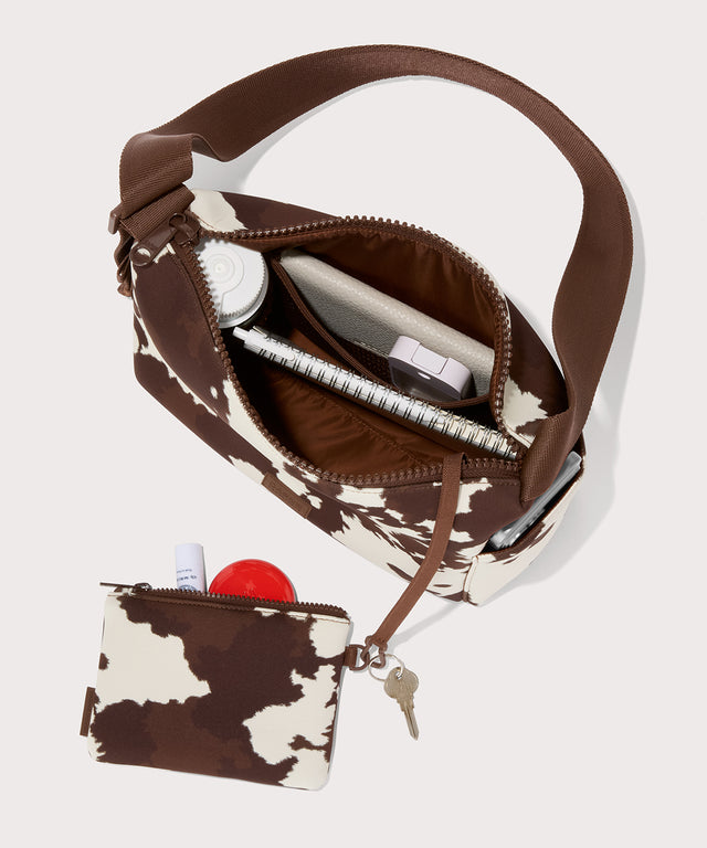 Shoulder bag in a cow print seen from the top down view. 