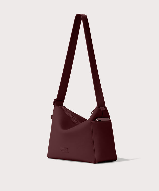 Shoulder bag in a fiery, a deep brown with purple undertones reminiscent of maroon seen from the angle view showing phone pocket.
