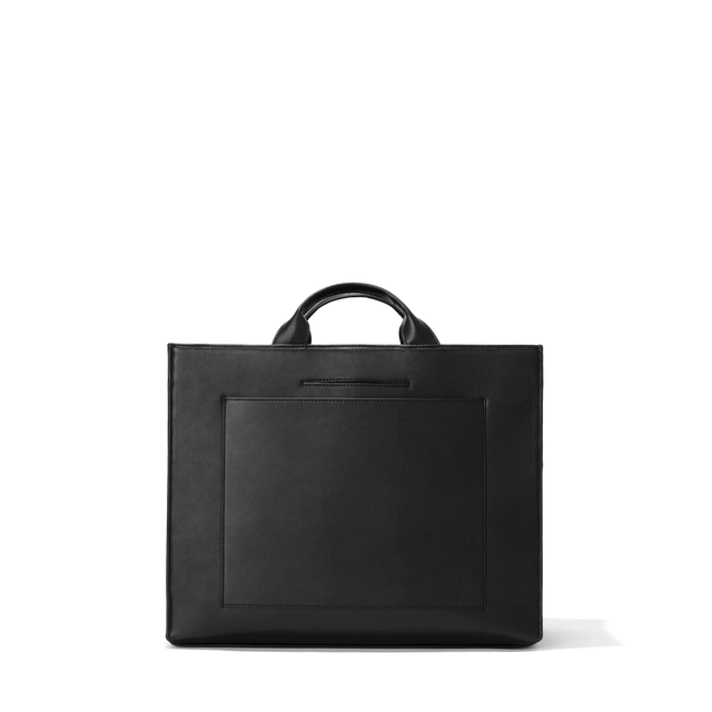 Dagne Dover medium vegan Daily Tote in black revealing the exterior phone pocket and exterior luggage sleeve.