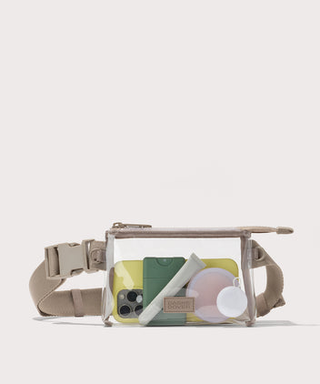 Clear crossbody bag with beige strap on a white background with phone and accessories  Stadium compliant. 